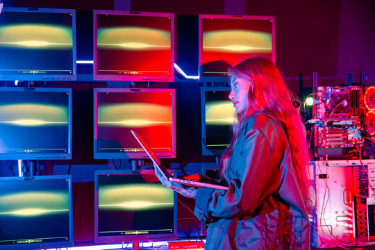 Asian woman holding laptop computer with CCTV room she check maintain security in monitor display, Hacker wearing a black jacket and has long red hair