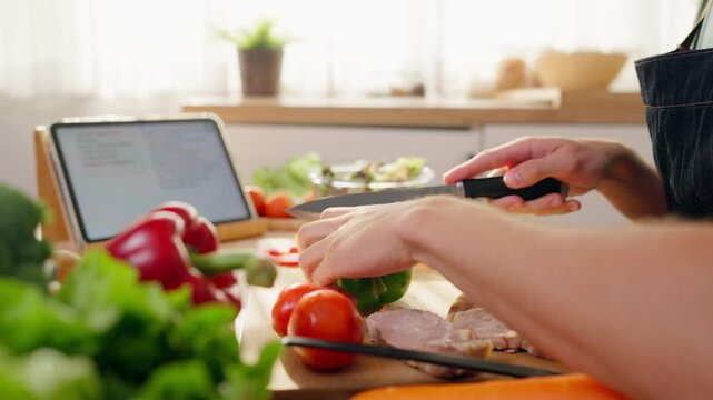 Close up of man using tablet to follow online recipe while cooking food. 