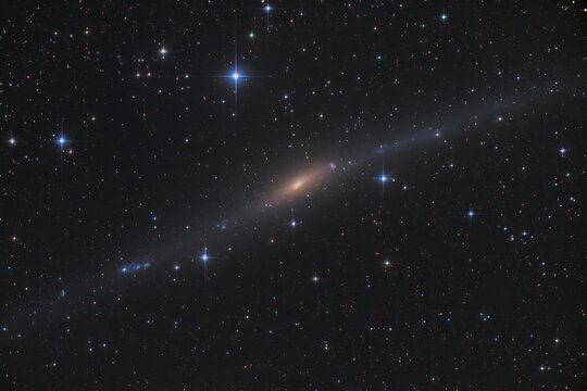 Spiral galaxy glowing in deep space surrounded by numerous bright twinkling stars against dark void