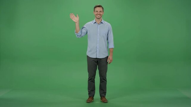 Friendly man waving hello with a smile on a green screen background, full body shot.