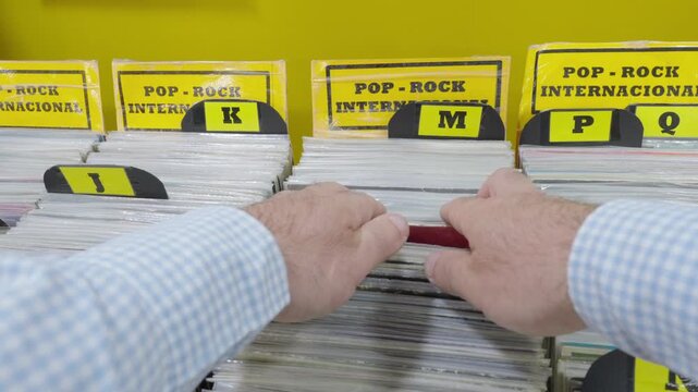 POV close up of businessman&rsquo;s hands browsing international pop rock vinyl records in a vintage record store, selecting classic albums in Spain.