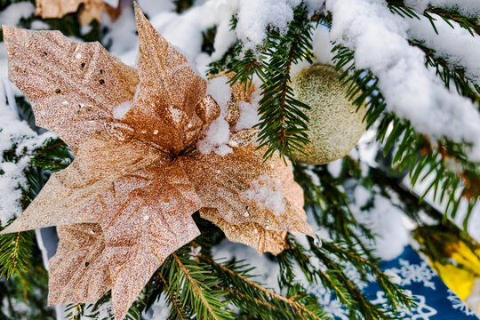 A decorated Christmas tree stands in the snow with ornaments and golden leaves. The scene captures the spirit of winter and winter holidays in a joyful way