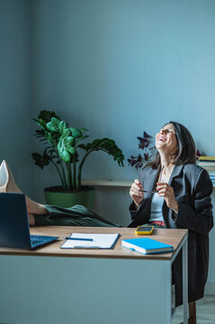 Happy businesswoman relaxes at her home office desk after a deal