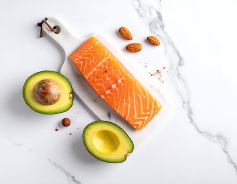 Fresh salmon fillet, avocado halves, and almonds arranged on a marble surface