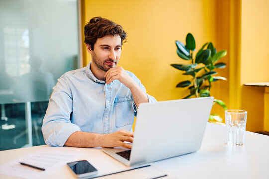 A focused businessman works on a laptop at the modern office