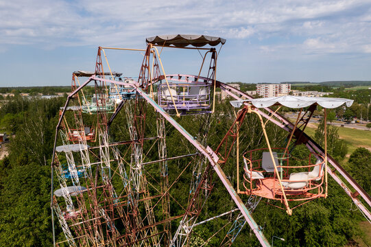 Aerial view of the historic Ferris wheel with colorful gondolas and a rusty metal structure set amidst lush green trees in Elektrenai, Vilnius County, Lithuania.