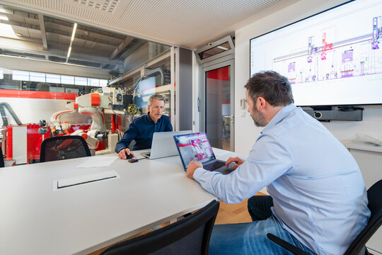 A mature man and a senior man plan automation in a factory office