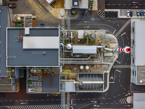Aerial view of an industrial facility with complex piping systems, storage tanks, and flat rooftops in Pico da Pedra, Azores, Portugal.
