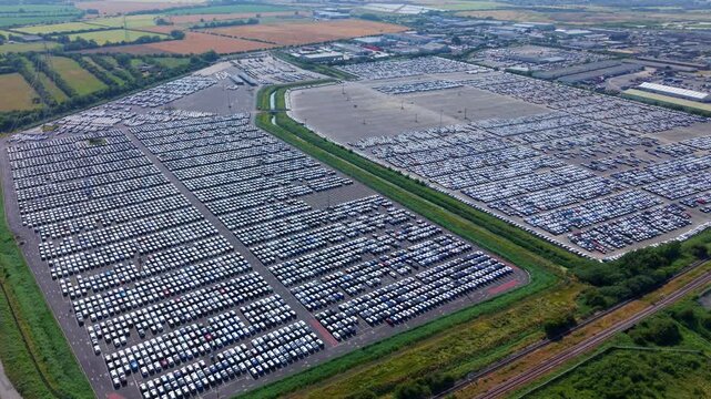 Aerial view of hundreds of new cars parked in uniform rows at a large distribution facility in Stallingborough, England, United Kingdom.