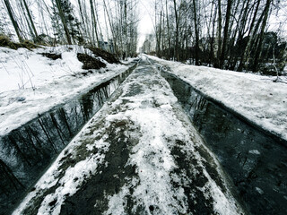 Obraz premium Melted snowy road in the forest in winter