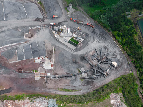 Aerial view of an industrial quarry site with processing machinery, conveyor belts, piles of gravel, and trucks in Sao Miguel, Acores, Portugal.