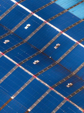 Aerial view of a large blue corrugated metal industrial roof with ventilation units and white and red trim lines in Sao Miguel, Acores, Portugal.