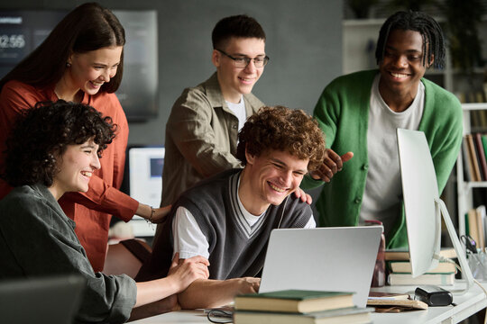Diverse students discuss a project on a laptop indoors