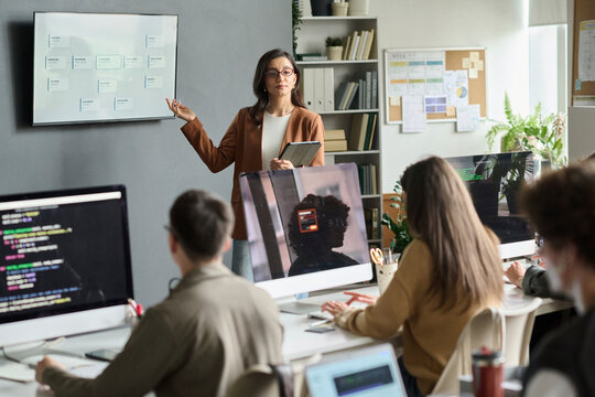 Female teacher explains programming to student group in classroom