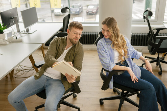 A businessman and a businesswoman discuss ideas in a modern office