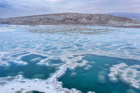 Aerial view of The Dead Sea with intricate salt formations and turquoise water against arid mountains in Beersheba, South District, Israel.
