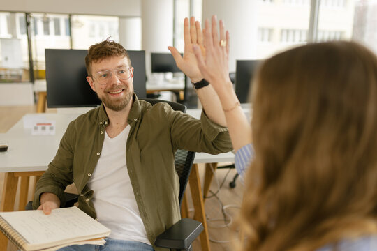 Man and woman give a high five in the modern office