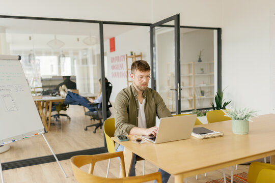 Male businessman works on laptop in a modern office