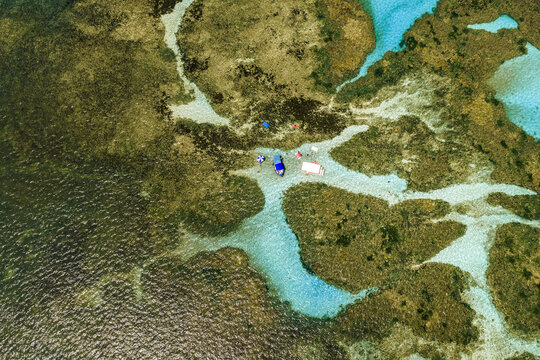Aerial view of Piscinas naturais em Ponta do Seixas with turquoise water, coral reefs, and small boats in Joao Pessoa, State of Paraiba, Brazil.