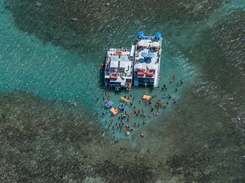 Aerial view of Piscinas naturais em Ponta do Seixas with catamarans and people swimming in clear turquoise water in Joao Pessoa, State of Paraiba, Brazil.