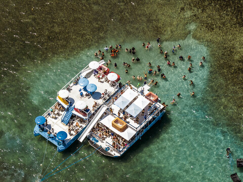 Aerial view of Piscinas naturais em Ponta do Seixas with two catamarans filled with tourists floating in clear turquoise water in Joao Pessoa, Paraiba, Brazil.