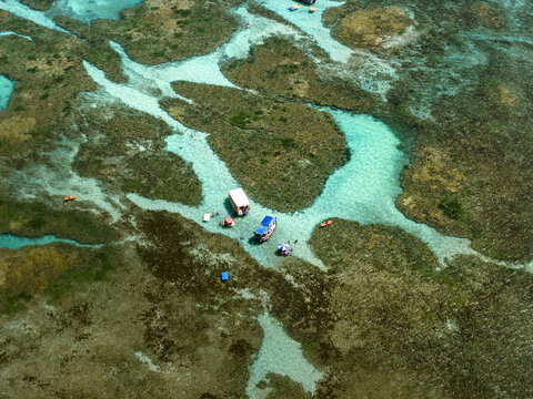 Aerial view of Piscinas naturais em Ponta do Seixas with turquoise water, coral reefs, and small boats in Joao Pessoa, State of Paraiba, Brazil.