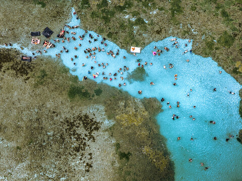 Aerial view of the natural pools at Ponta do Seixas with many people swimming in the turquoise water surrounded by coral reefs in Joao Pessoa, State of Paraiba, Brazil.