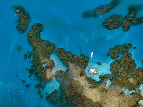 Aerial view of Piscinas Naturais em Ponta do Seixas, with a small boat floating in the clear turquoise water surrounded by coral reefs, Joao Pessoa, Paraiba, Brazil.
