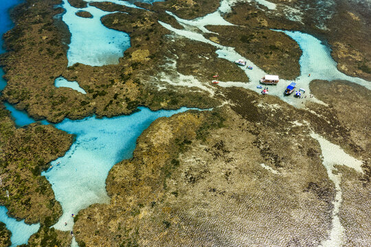 Aerial view of Piscinas naturais em Ponta do Seixas with turquoise water pools, coral reefs, and small boats in Joao Pessoa, Paraiba, Brazil.