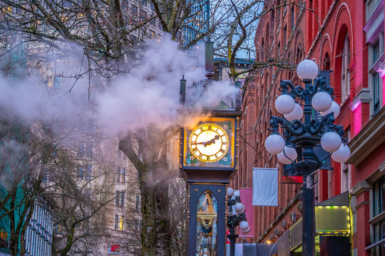 Famous steam clock emitting plume of steam on historic brick street during twilight in Gastown, Vancouver