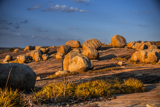 View of Lajedo de Pai Mateus with large granite boulders scattered across the rocky landscape under a clear blue sky in Cabaceiras, Paraiba, Brazil.