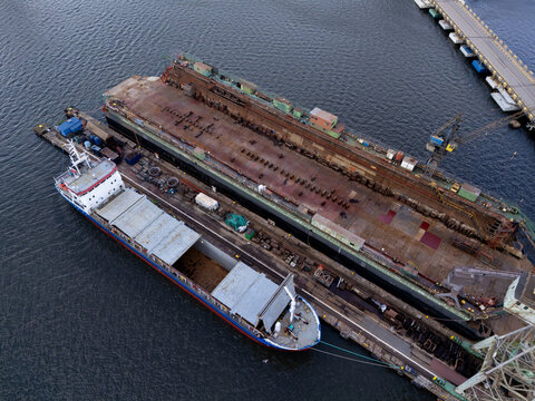 Aerial view of the historic Stocznia Gdanska shipyard featuring large industrial dry docks, cargo ships, and cranes along the waterfront in Gdansk, Wojewodztwo pomorskie, Poland.