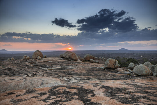 View of the unique rock formations at Lajedo de Pai Mateus during a dramatic sunset with a colorful sky and vast landscape in Cabaceiras, Paraiba, Brazil.
