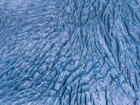 Aerial view of the deep blue crevasses and textured ice formations of the Fjallsarlon glacier in Sveitarfelagid Hornafjordur, Iceland.