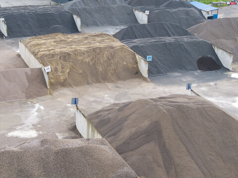 Aerial view of the Wytwornia mas bitumicznych Skawina asphalt plant featuring large stockpiles of gravel and aggregate stored in concrete bays in Skawina, Lesser Poland Voivode, Poland.