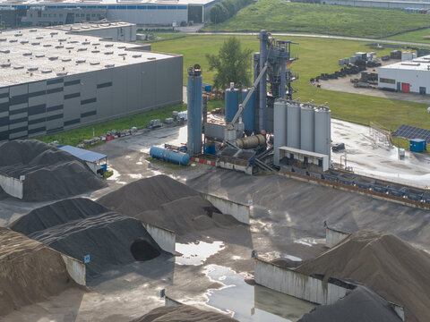 Aerial view of the bituminous mass plant featuring industrial silos, machinery, and large piles of aggregate materials stored in concrete bays in Skawina, Lesser Poland Voivode, Poland.