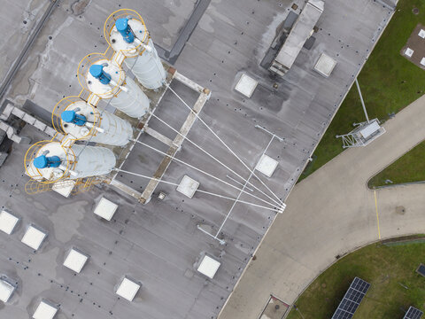 Aerial view of the Dragon Poland industrial facility featuring white silos with blue tops and intricate piping on the roof in Skawina, Wojewodztwo malopolskie, Poland.