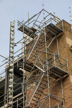 View of metal scaffolding erected against a historic brick building in the Netherlands.