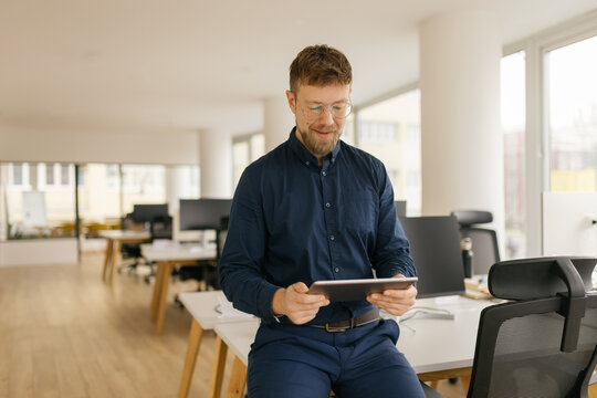 Confident businessman working on digital tablet in modern office