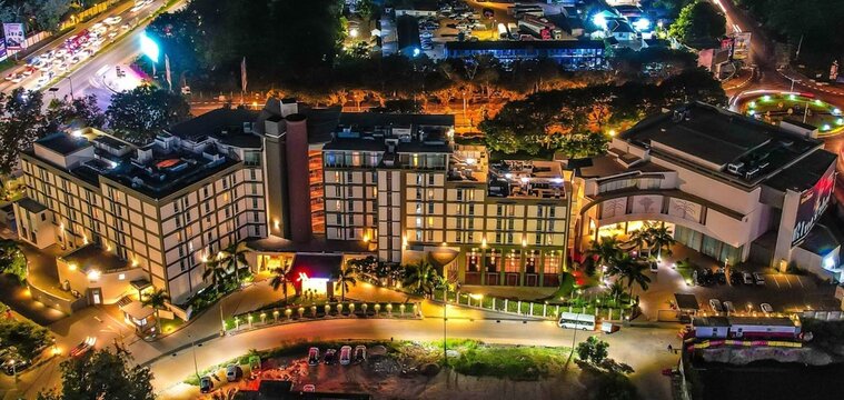 Aerial view of the illuminated Accra Marriott Hotel at night, featuring modern architecture, surrounding urban roads with traffic, and lush greenery in Ghana.