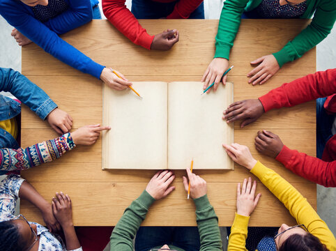 Group of children brainstorming around an open book on a table  