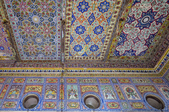 View of the intricate, colorful floral and geometric tile patterns adorning the ceiling and walls of the historic Faiz Mahal in Khairpur, Sindh, Pakistan.
