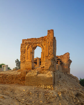 View of the ancient brick ruins of the Mohammad bin Qasim Mosque featuring a prominent archway and weathered masonry situated on a mound in Arror, Sindh, Pakistan.