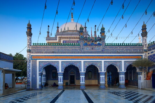 View of the Shrine of Shah Abdul Latif Bhittai with its intricate blue tile work, white dome, and arched entrance in Bhit Shah, Sindh, Pakistan.