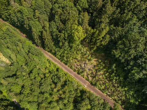 Aerial view of the railway track cutting through the dense forest of Bystricka dolina in Velka Fatra, Dolny Harmanec, Banskobystricky kraj, Slovakia.