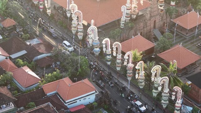 Aerial view of Pura Agung Petilan with traditional Balinese penjor decorations lining the street in Kecamatan Denpasar Timur, Bali, Indonesia.