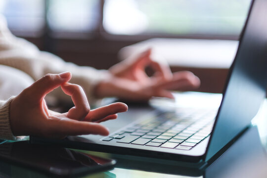 Closeup image of a woman hands in lotus pose over laptop computer for stress relief concept