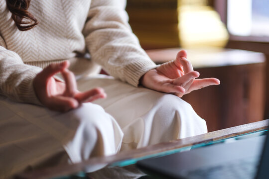 Closeup image of a woman hands in lotus pose over laptop computer for stress relief concept