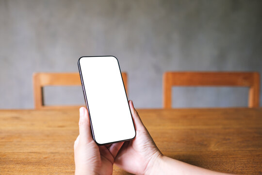 Mockup image of a woman holding mobile phone with blank desktop screen