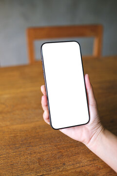Vertical mockup image of a woman holding mobile phone with blank desktop screen